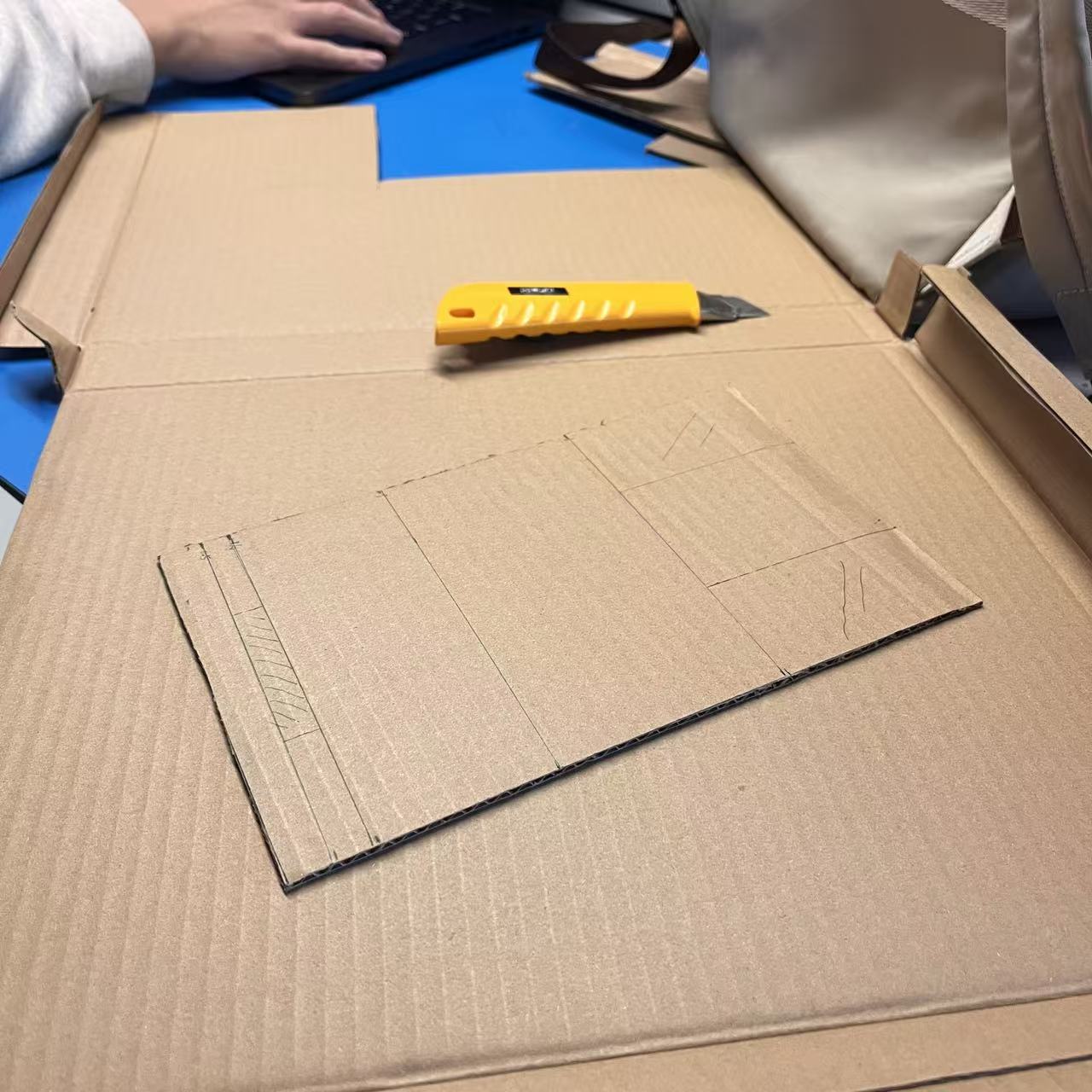 Cutting basic cardboard pieces to form the initial phone stand structure.